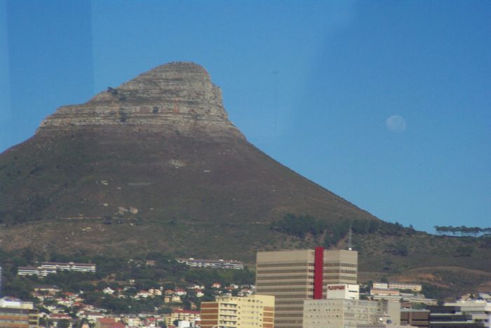 The large, nearly full moon accents the beauty of the landscape that frames it.